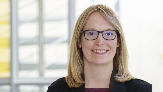 Portrait: Frau mittleren Alters. Sie hat dunkelblonde schulterlanges Haar. Trägt eine Brille. Hat einen schwarzen Blazer an.