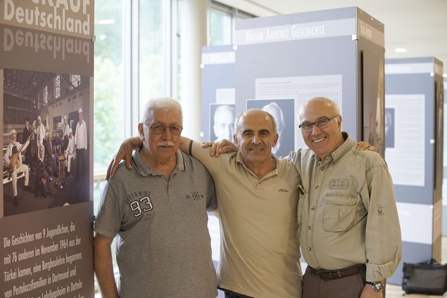 Three friends standing together in a photo exhibition.