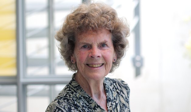 Dr. Heidrun Mollenkopf: Alte Frau mit kurzen braunen, gelockten Haaren. Sie trägt ein schwarz-weiß gemusterte Bluse.