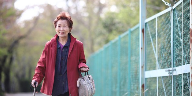 Japanische ältere Frau mit Gehstock und Einkaufstasche