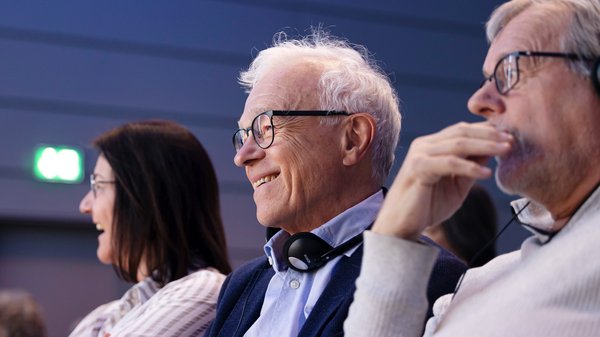 ©BAGSO_Lys Zwei Männer und eine Frau im Zuschauerraum. Ein Mann im vorderen Bereich des Fotos hat Kopfhörer an.