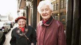 Zwei alte Frauen stehen in der Stadt auf einem Bürgersteig.