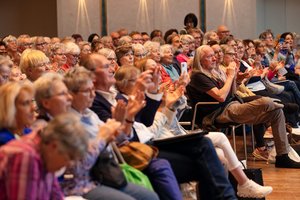 Blick in ein bunt gemischtes Publikum. Es klatscht gerade.