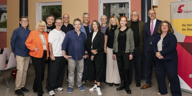 Ein Gruppenbild mit Männern und Frauen, neben Ihnen steht ein Roll Up der BAGSO.