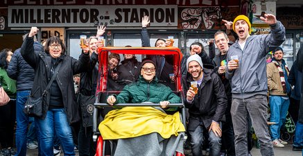 Freudiger Senior fährt mit Rikscha inmitten ausgelassener St. Pauli Fans.