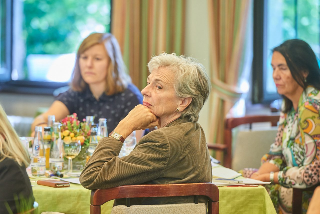 Drei Teilnehmerinnen sitzen an einem Tisch und hören konzentriert zu.