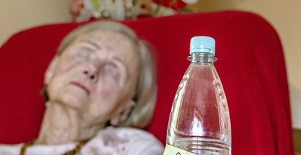 Alte Dame, schläft, halbvolle Wasserflasche, Zettel "bitte austrinken"