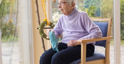 Seniorin pausiert beim Fensterputzen und schaut aus dem Fenster