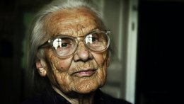 Eine sehr alte Frau mit Brille schaut in die Kamera.