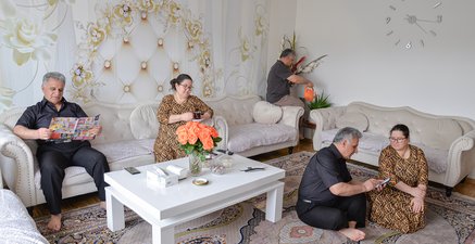 Frau gelb Fotomontage dupliziert zwei mal im Wohnzimmer. Trinkt Tee. Sitzt auf Boden. Mann schwarz dupliziert 