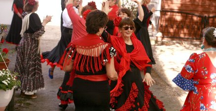 Frauen zwischen 50 und 75 tanzen in Flamenco-Kleidern iim Garten.