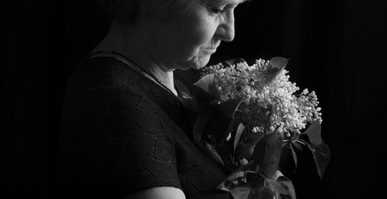 Ältere Frau mit Strauß Flieder in der Hand