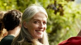 Eine lächelnde ältere Frau mit langen grauen Haaren