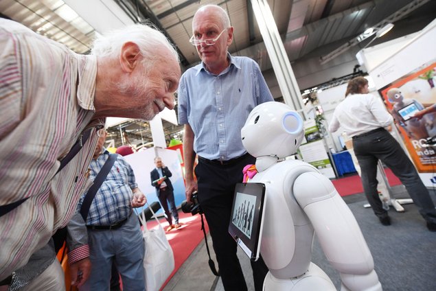 An older person looking curiously at the nursing robot Pepper.
