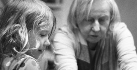 Eine Seniorin zeigt ihrer Enkelin und ihrer Urenkelin Malutensilien
