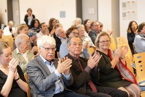 Participants at BAGSO conference applaud. Jens-Peter Kruse and Katrin Markus from the BAGSO board, Franz Müntefering, the former BAGSO chairman, and Nicole Zündorf-Hinte, policy officer at the BMFSFJ, can be seen.