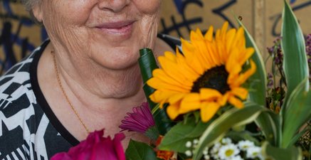 Ältere Frau lächelt mit Blumenstrauß in der Hand
