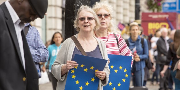 Zwei Frauen halten jeweils ein blaues Papier in der Hand, auf dem die Sterne Europas zu einem Herz angeordnet sind.