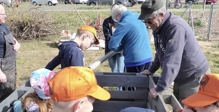 Kinder und Senioren bauen ein Hochbeet, befüllen und bepflanzen es