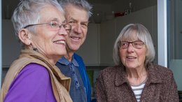 Zwei ältere Frauen und ein Mann stehen vor einer Terassentür.