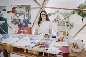 Eine junge Frau steht an einem Messestand.
