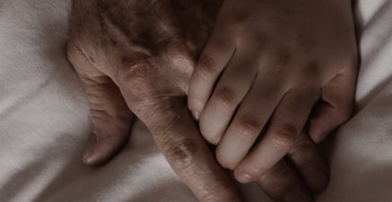 Junge Hand liegt auf einer alten Hand.