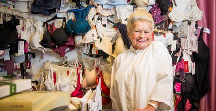 Ältere Frau steht strahlend inmitten von Dessous