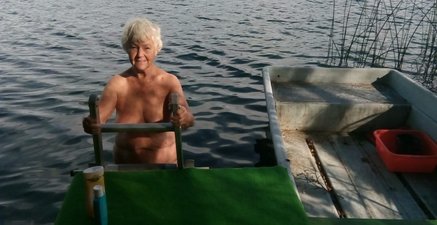 Ältere Frau steigt nackt auf einer Leiter aus einem See.