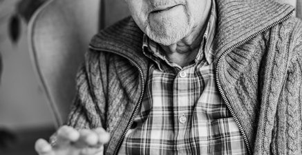 Älterer Herr im Sessel hält ein Tablet in der Hand