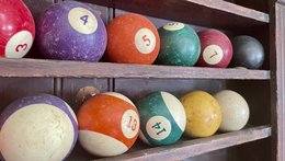 In einem Wandregal liegen alte Billiardkugeln