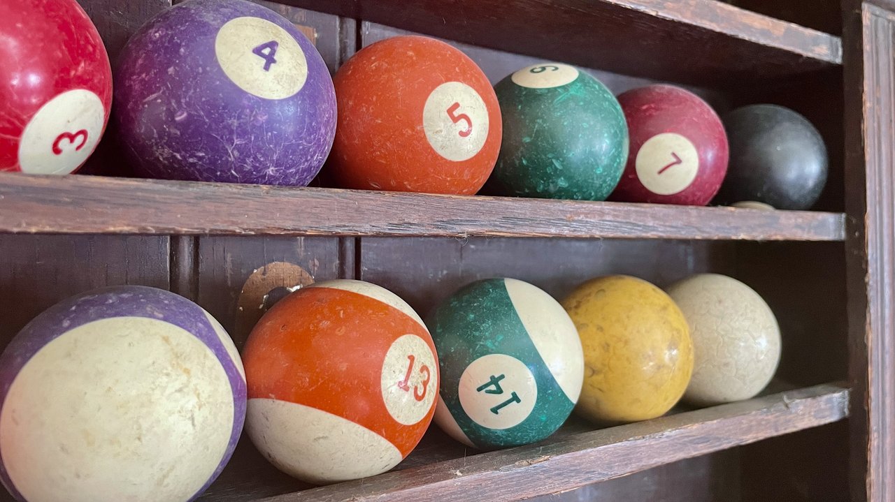 In einem Wandregal liegen alte Billiardkugeln