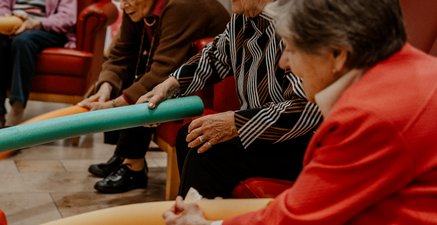 Vier ältere Frauen mit Poolnudel in der Hand bei der Gymnastik