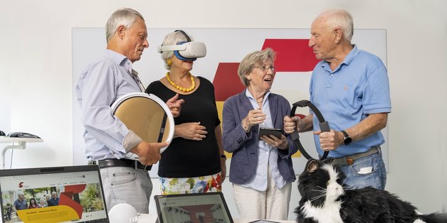 Vier ältere Menschen probieren KI-Technik aus. 