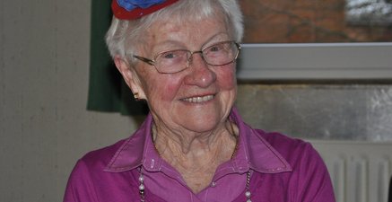 Ältere Frau mit lustigem Hütchen auf dem Kopf