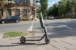 Ein E-Roller steht vor einem Ampel-Überweg.