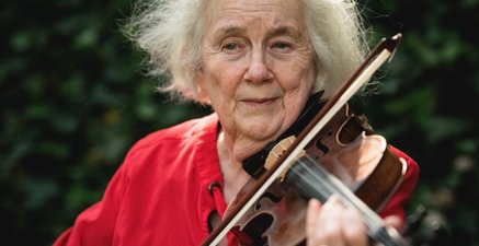Ältere Frau spielt Geige im Garten