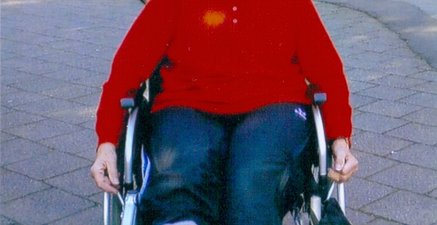 Ältere Frau sitzt mit eingegipstem Fuß im Rollstuhl, der von einem Jungen geschoben wird