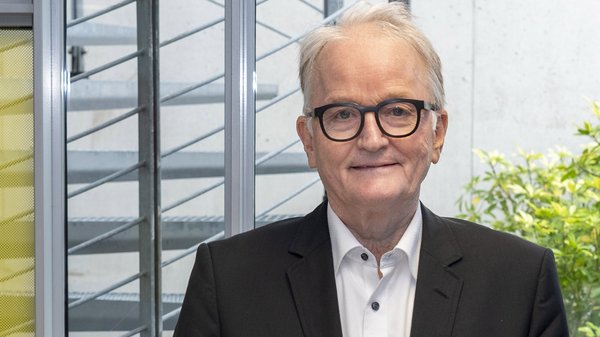 Vorstandsmitlied Norbert Theobald: Älterer Mann mit grauem Haar und markanter Brille. Er trägt ein dunkles Jackett und ein weißes Hemd