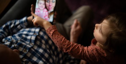 Älterer Mann und kleines Mädchen schauen sich Bilder auf dem Tablet an. Sicht von oben auf die Szene.