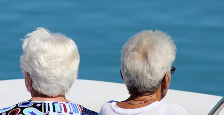 Zwei grauhaarige Frauen von hinten zu sehen auf einer Bootstour bei strahlendem Sonnenschein