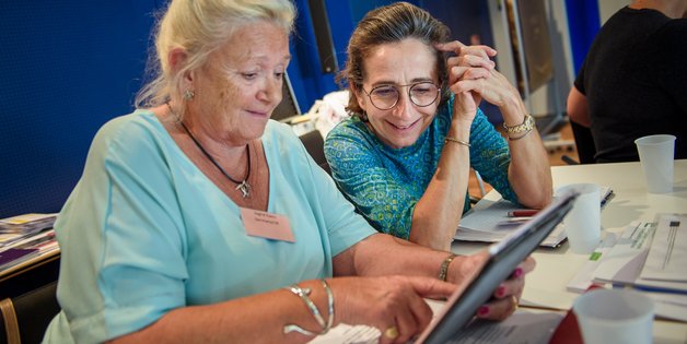 Zwei ältere Frauen sitzen vor einem Tablet