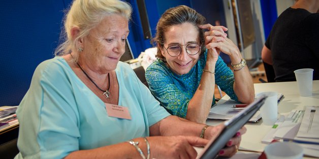 Zwei ältere Frauen sitzen vor einem Tablet