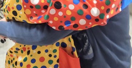 Eine junge Frau im Clownskostüm tanzt mit einem 80-jährigen mit Hut