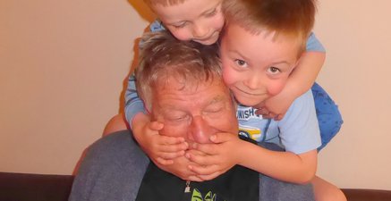 Zwei Enkelkinder turnen auf dem Opa