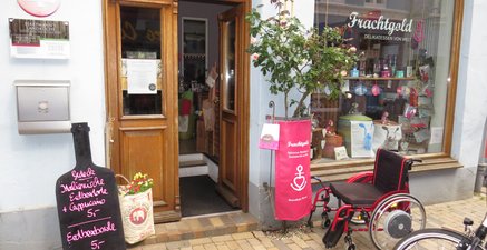 Ein roter Rolli steht leer und angeschlossen vor dem sehr einladenden Delikatessen-Geschäft mit dem Namen „Frachtgo
