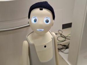 Portrait eines Roboters mit Pudelmütze und Kulleraugen.