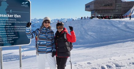 Zwei ältere Frauen in Skianzügen stehen im Schnee eines Skigebietes