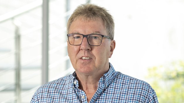 Portrait Rolf Hönen: Ein älterer Mann mit kurzem, grau meliertem Haar. Er trägt ein kariertes Hemd