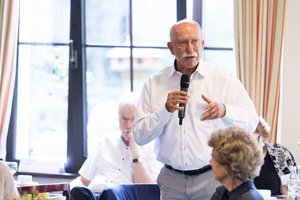 Ein älterer Mann aus der Zuhörerschaft spricht in ein Mikrofon.
