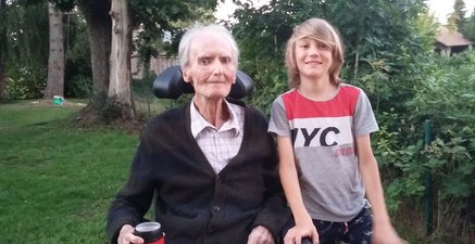 Von schwerer Krankheit gezeichneter älterer Mann und sein Enkel sind gemeinsam im Garten.